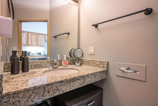 bathroom featuring a textured wall and vanity