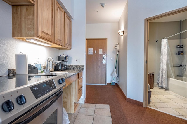 kitchen featuring baseboards, stainless steel electric range oven, a sink, and light tile patterned floors