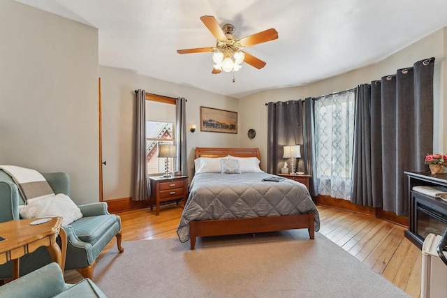 bedroom with light wood-type flooring, multiple windows, and a ceiling fan