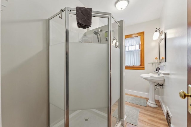 full bath featuring a stall shower, visible vents, baseboards, and wood finished floors