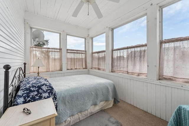 bedroom featuring wood walls, carpet, wooden ceiling, and a ceiling fan