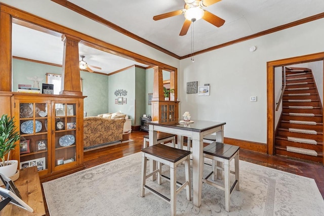 dining space featuring baseboards, ceiling fan, wood finished floors, stairs, and crown molding