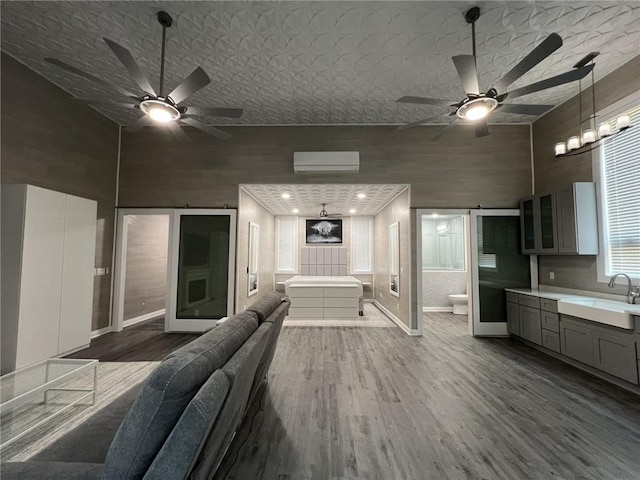 interior space featuring a wall unit AC, a towering ceiling, a sink, and wood finished floors