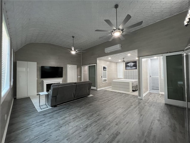 unfurnished living room with lofted ceiling, a barn door, a fireplace, wood finished floors, and an AC wall unit