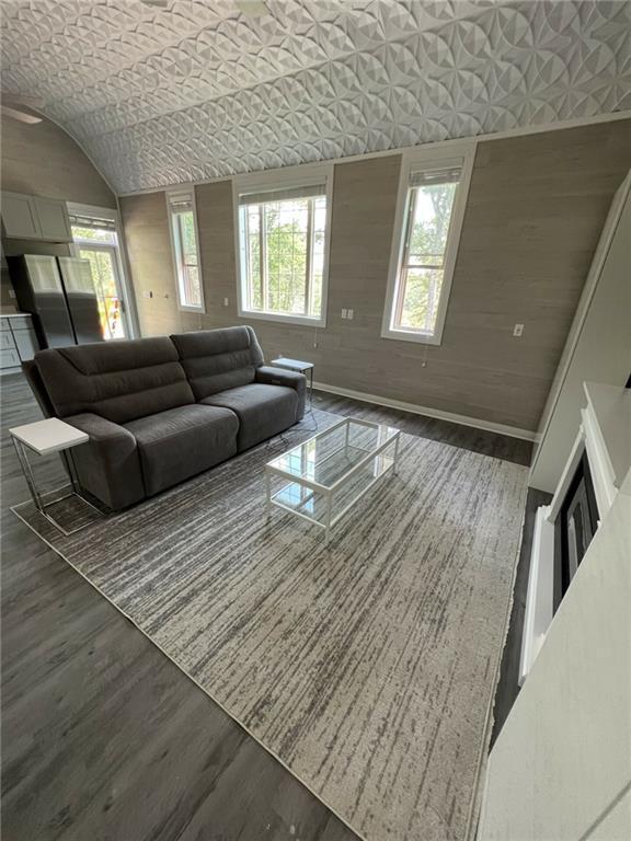 living room with lofted ceiling, baseboards, and wood finished floors