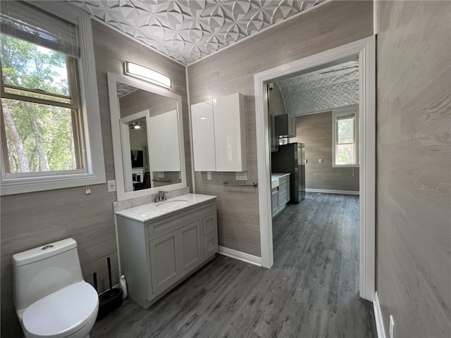 bathroom featuring baseboards, vanity, toilet, and wood finished floors