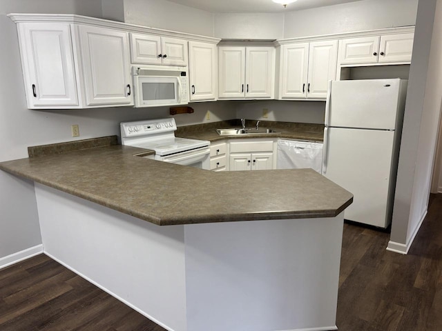 kitchen with dark countertops, white appliances, white cabinets, and a sink