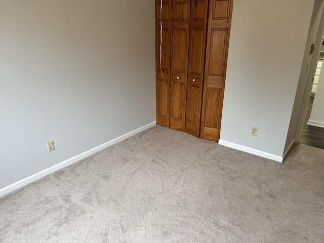 unfurnished bedroom with carpet, baseboards, and a closet