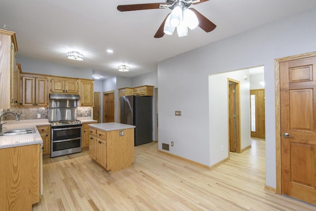 kitchen featuring light countertops, freestanding refrigerator, a sink, double oven range, and under cabinet range hood