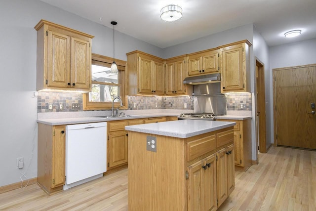 kitchen with light wood finished floors, light countertops, a sink, dishwasher, and under cabinet range hood