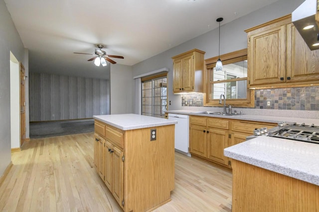 kitchen featuring a center island, light wood finished floors, light countertops, white dishwasher, and a sink