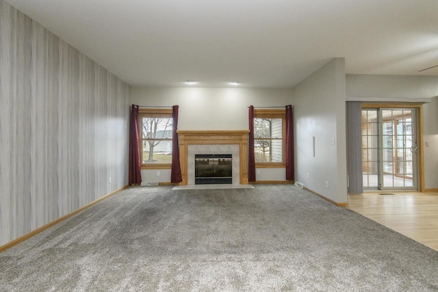 unfurnished living room featuring a tile fireplace, carpet flooring, and baseboards