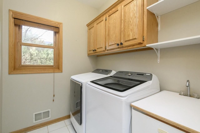 clothes washing area with cabinet space, light tile patterned floors, baseboards, visible vents, and washing machine and clothes dryer