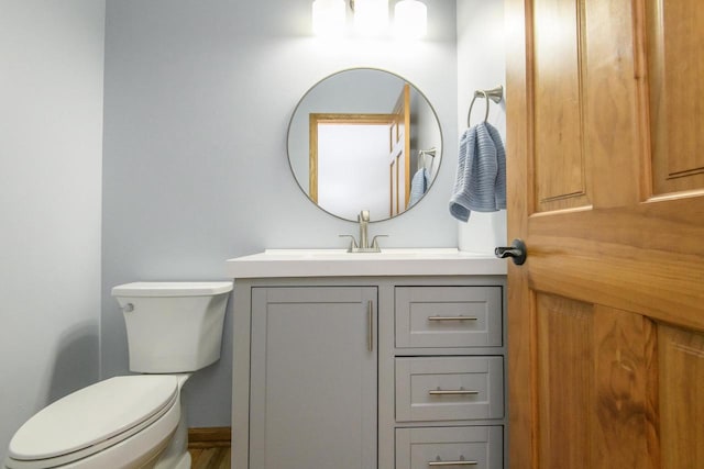 half bath with vanity, toilet, and baseboards