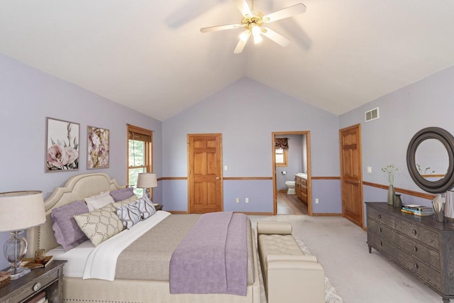 bedroom featuring light carpet, visible vents, a ceiling fan, lofted ceiling, and ensuite bath