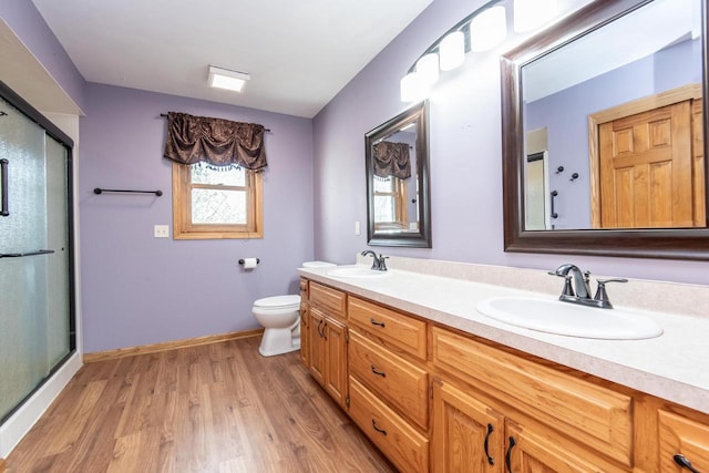 full bathroom with toilet, a shower stall, a sink, and wood finished floors