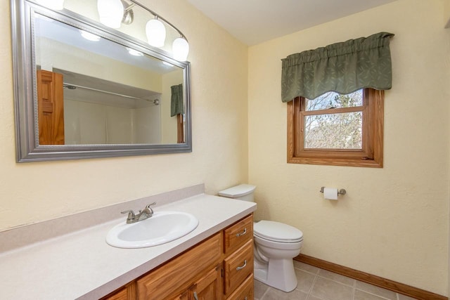 full bath with toilet, tile patterned floors, baseboards, and vanity