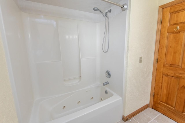 bathroom featuring a combined bath / shower with jetted tub, a textured wall, baseboards, and tile patterned floors