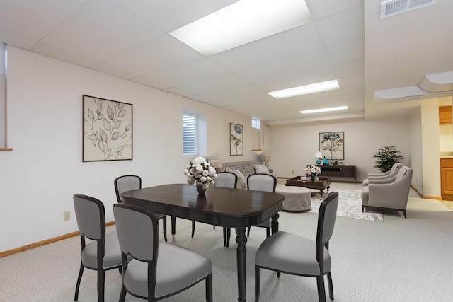 dining area with light carpet, baseboards, visible vents, and a paneled ceiling