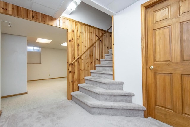 staircase featuring baseboards, carpet, and wooden walls