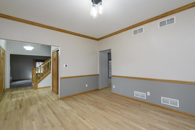 spare room featuring stairway, visible vents, and wood finished floors