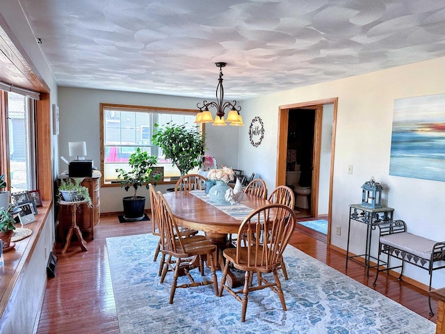 dining area with a textured ceiling, hardwood / wood-style flooring, and an inviting chandelier