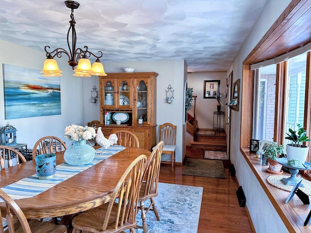 dining space with stairs, a notable chandelier, and wood finished floors