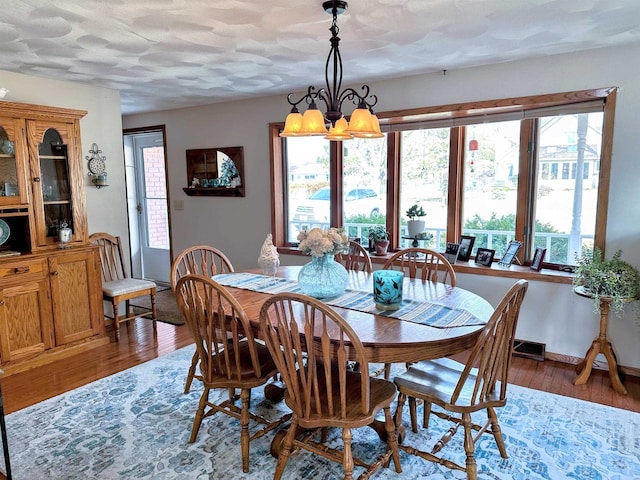 dining space featuring an inviting chandelier, a textured ceiling, baseboards, and wood finished floors