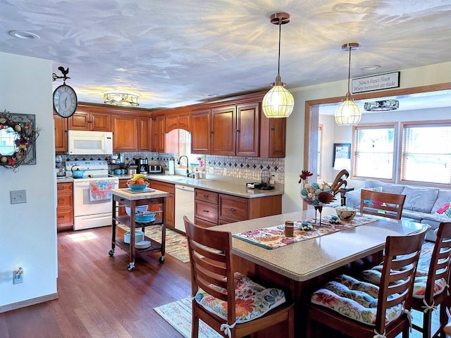 kitchen featuring light countertops, white appliances, a healthy amount of sunlight, and a breakfast bar area