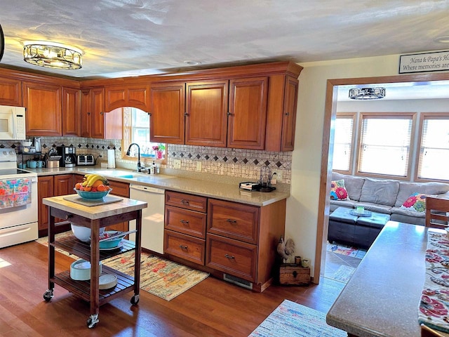 kitchen featuring white appliances, brown cabinetry, wood finished floors, light countertops, and a sink