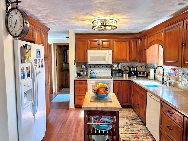 kitchen featuring light wood finished floors, butcher block counters, backsplash, a sink, and white appliances