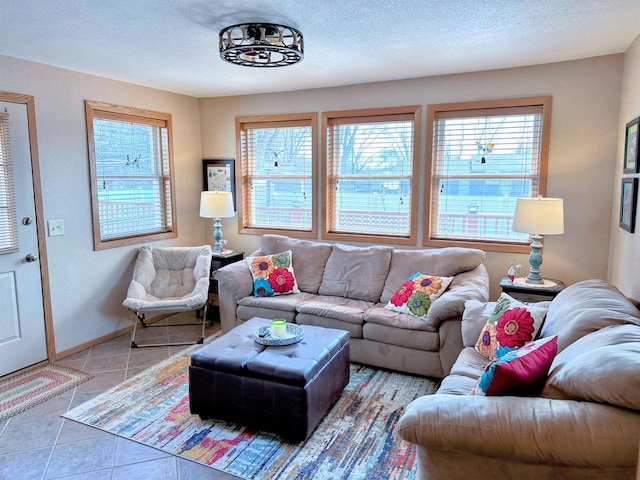 living room with light tile patterned floors, a textured ceiling, baseboards, and a wealth of natural light