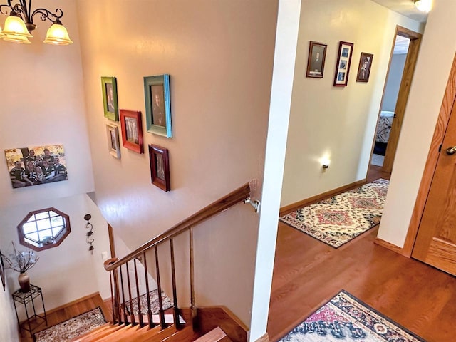 staircase with an inviting chandelier, baseboards, and wood finished floors