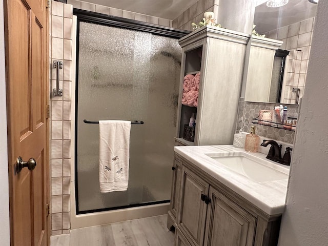 full bath with a shower stall, backsplash, wood finished floors, and vanity