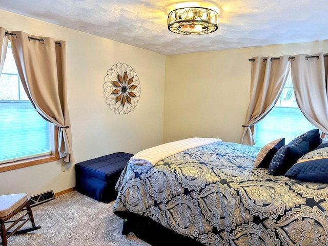 bedroom with a textured ceiling, carpet floors, visible vents, and baseboards