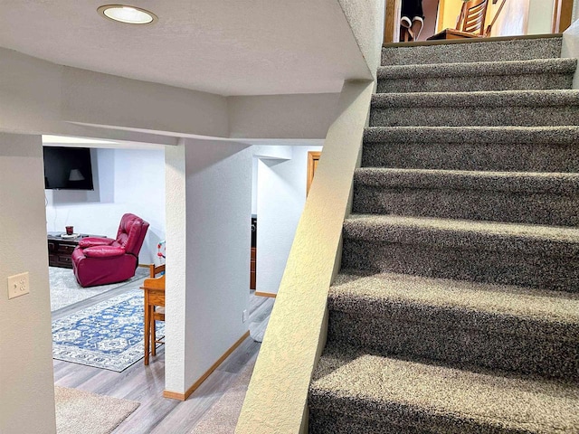 staircase featuring baseboards and wood finished floors