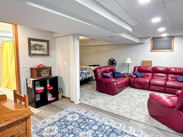 living room featuring a paneled ceiling, recessed lighting, baseboards, and wood finished floors