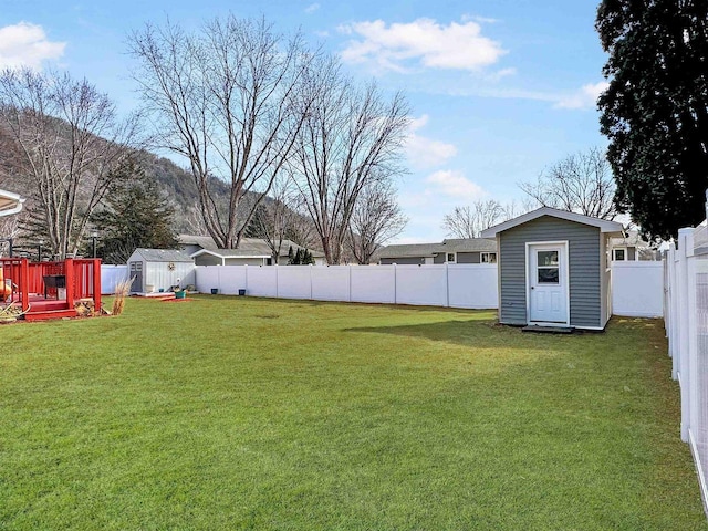 view of yard with a storage shed, an outbuilding, and a fenced backyard