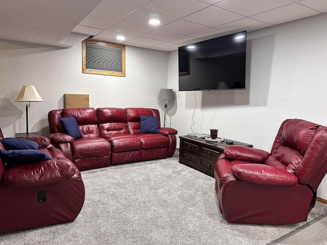 living area with a paneled ceiling, carpet flooring, and a textured wall