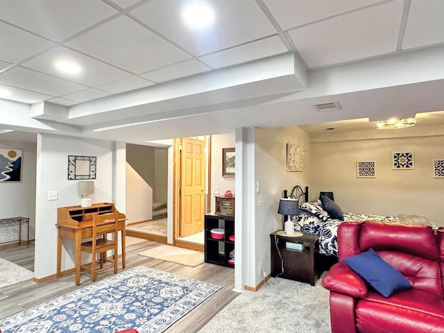 living area with visible vents, wood finished floors, a paneled ceiling, and baseboards