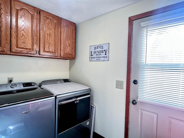 clothes washing area featuring washing machine and dryer and cabinet space