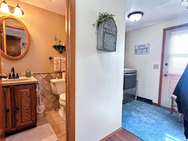 bathroom with wainscoting, toilet, tile patterned floors, vanity, and tile walls