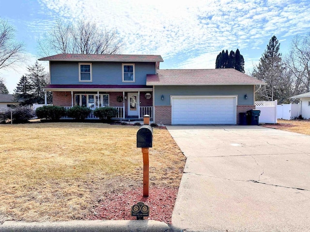 traditional-style house featuring a garage, concrete driveway, fence, a front lawn, and brick siding