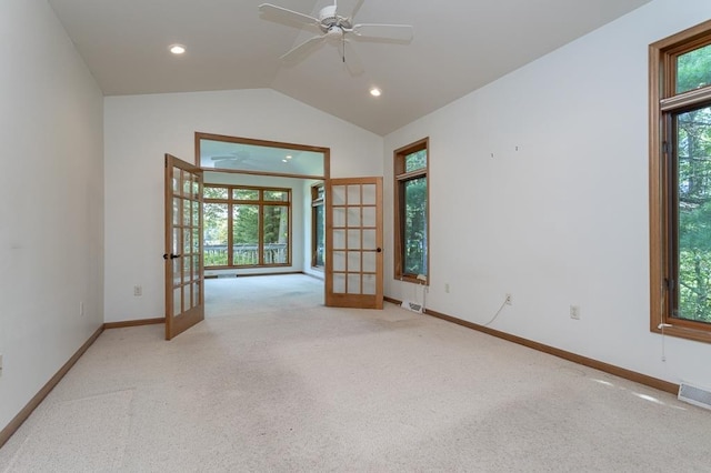 carpeted empty room featuring vaulted ceiling, french doors, and a healthy amount of sunlight