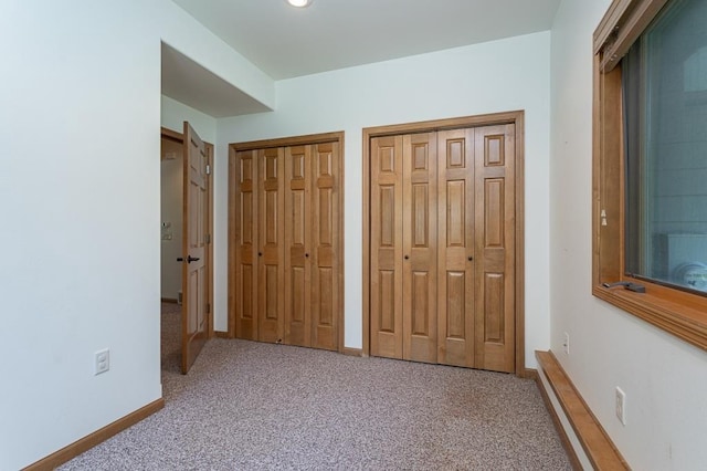 unfurnished bedroom featuring carpet, two closets, and baseboards