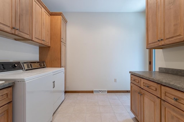 laundry area featuring cabinet space, light tile patterned floors, baseboards, visible vents, and washing machine and clothes dryer