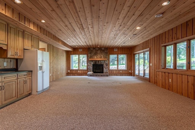 unfurnished living room with light carpet, wooden ceiling, wood walls, a fireplace, and recessed lighting