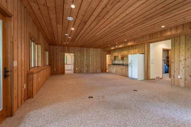 unfurnished living room with wooden ceiling, recessed lighting, wooden walls, visible vents, and carpet