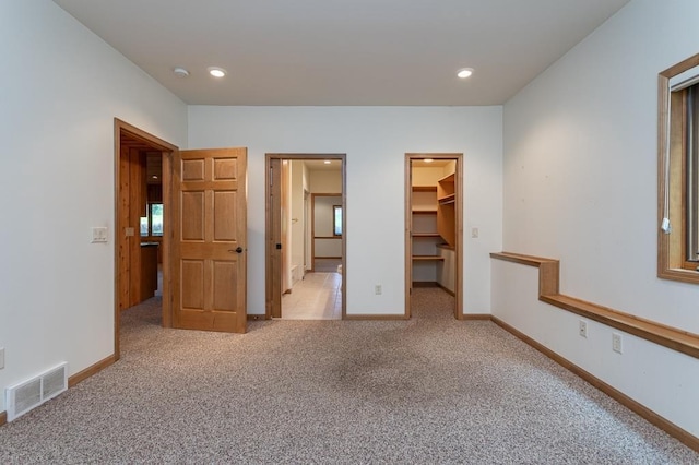 unfurnished bedroom with recessed lighting, carpet flooring, visible vents, baseboards, and a spacious closet