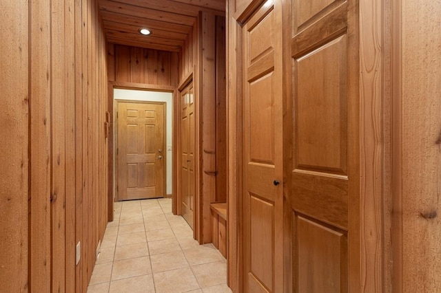 corridor featuring light tile patterned flooring and wooden walls